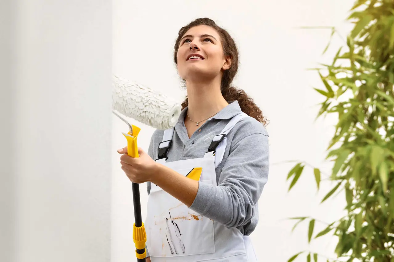 Tradesperson, painter using a roller to paint a house facade, Sto facade paint